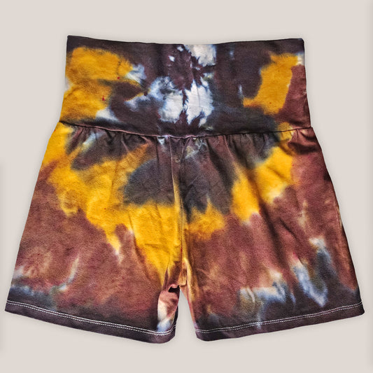 Tie-dye shorts with brown, yellow, and white pattern on a plain background