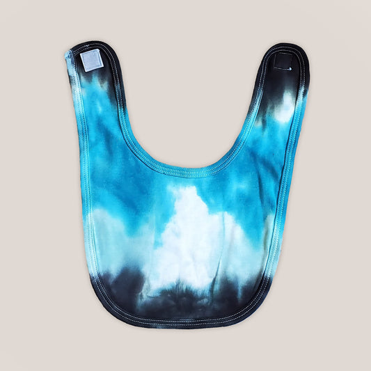 An aqua blue tie dye organic baby bib with velcro closure.