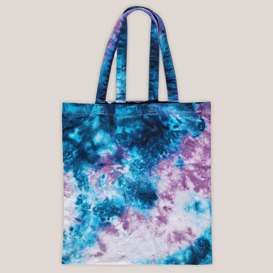 Tie-dye tote bag with blue and purple patterns on a beige background