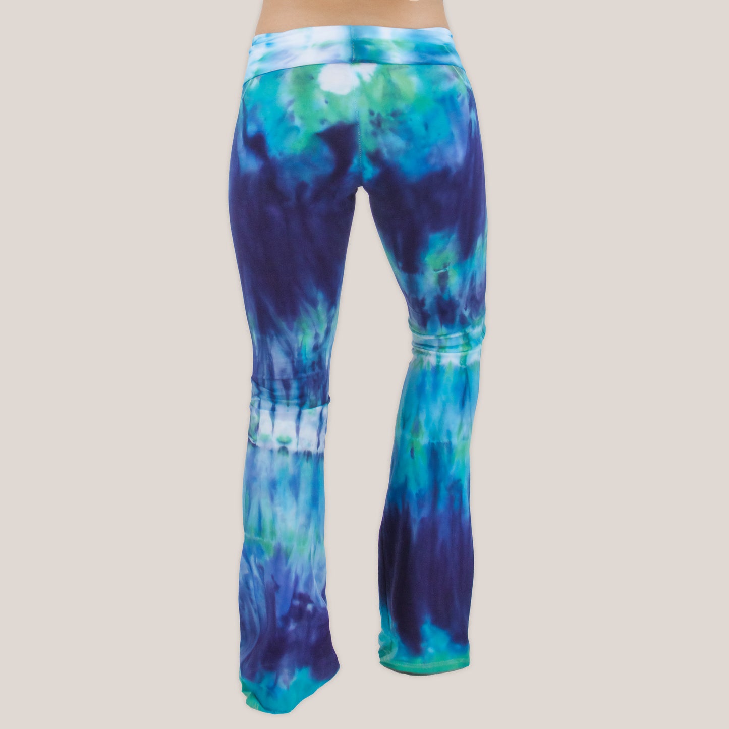 Woman wearing the Galapagos Islands tie dye yoga pants that features hand-dyed hues of navy blue, teal, and aqua.  These pants include a fold over waistband that is also comfortable as maternity wear.