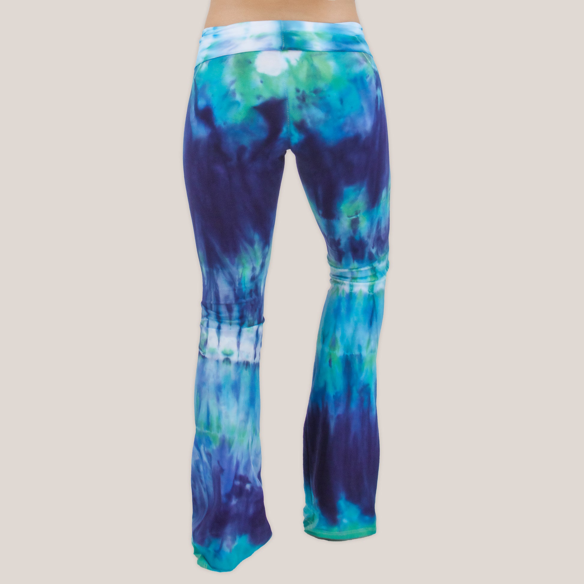 Woman wearing the Galapagos Islands tie dye yoga pants that features hand-dyed hues of navy blue, teal, and aqua.  These pants include a fold over waistband that is also comfortable as maternity wear.