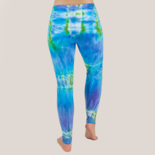 Woman wearing the Grenada tie dye leggings that feature hues of aqua, lavender, and emerald by Akasha Sun