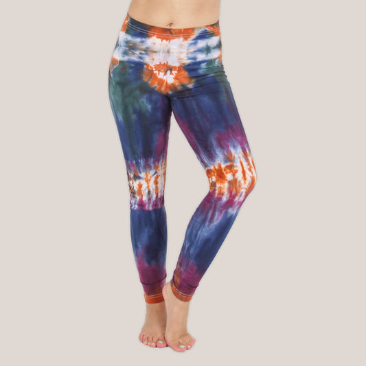 Woman wearing the Meteor tie dye leggings that feature the hues orange, navy, purple, and green by Akasha Sun