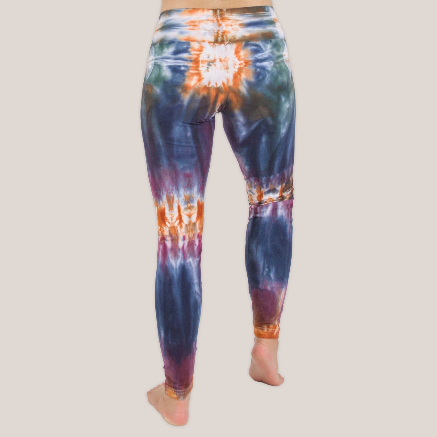 Woman wearing the Meteor tie dye leggings that feature the hues orange, navy, purple, and green by Akasha Sun