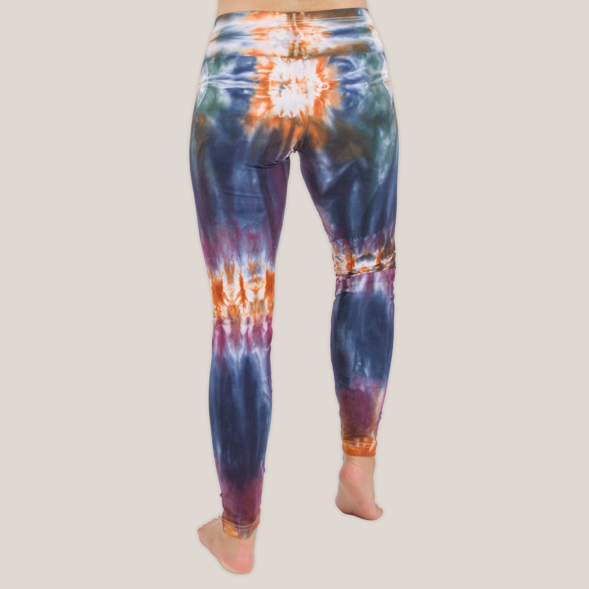Woman wearing the Meteor tie dye leggings that feature the hues orange, navy, purple, and green by Akasha Sun