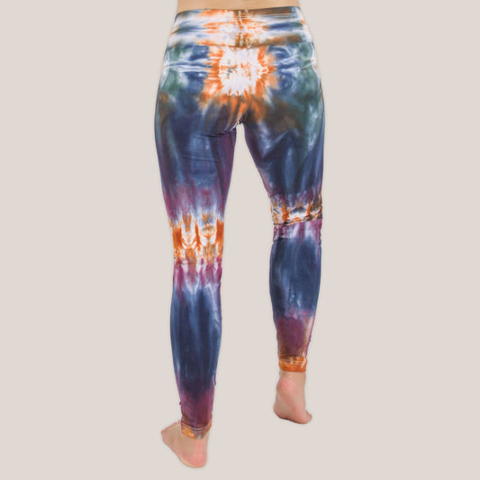 Woman wearing the Meteor tie dye leggings that feature the hues orange, navy, purple, and green by Akasha Sun