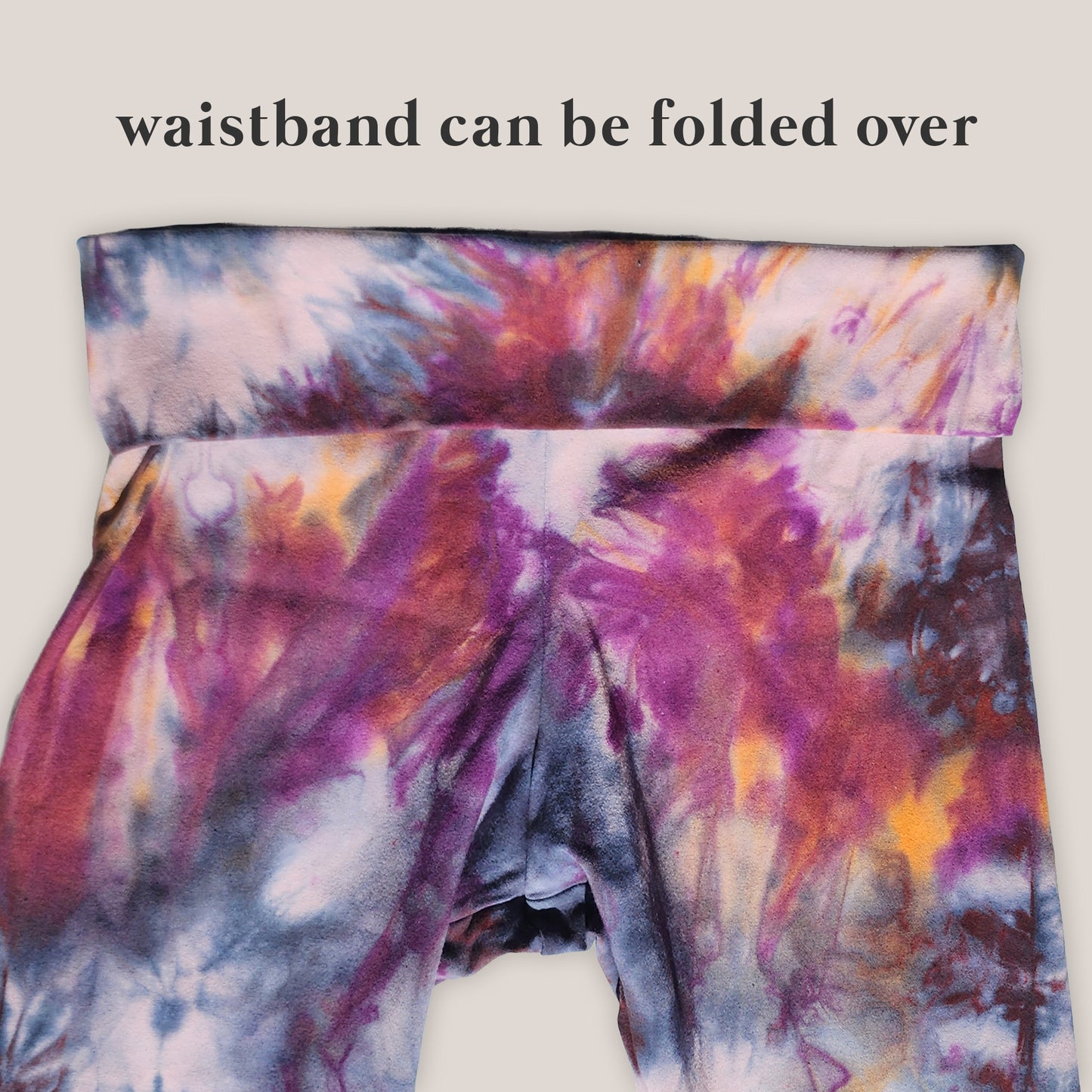 Colorful tie-dye yoga pants with a folded over waistband on a light background