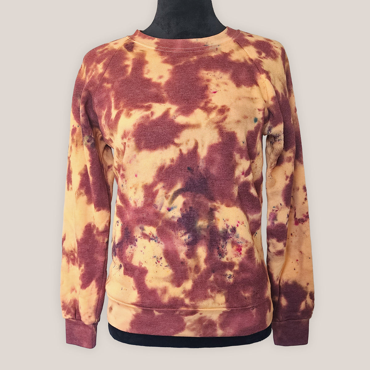 Tie-dye sweatshirt with an orange marbled pattern on a plain background