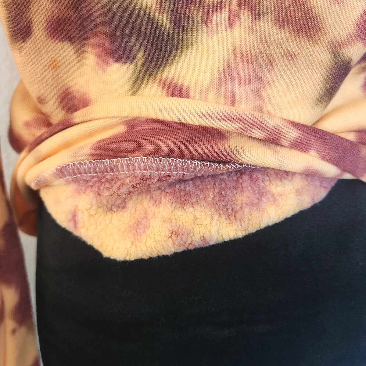Close-up of a tie-dye orange sweatshirt with fleece interior