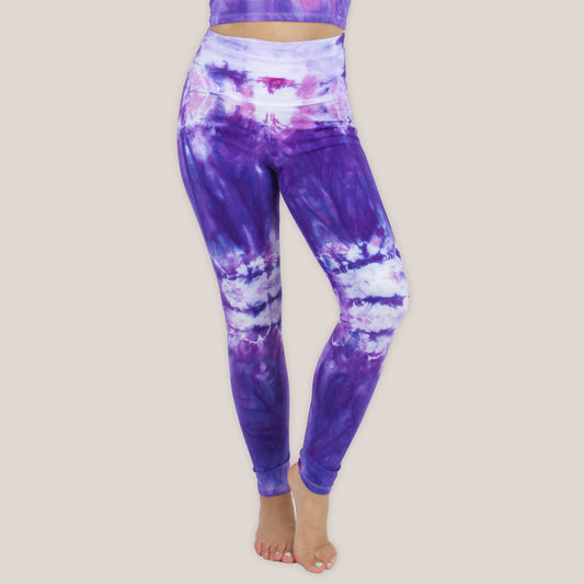 Woman wearing the Saint-Tropez tie dye leggings that feature a fold over waistband. The colors in these pants include purple, pink, and white.