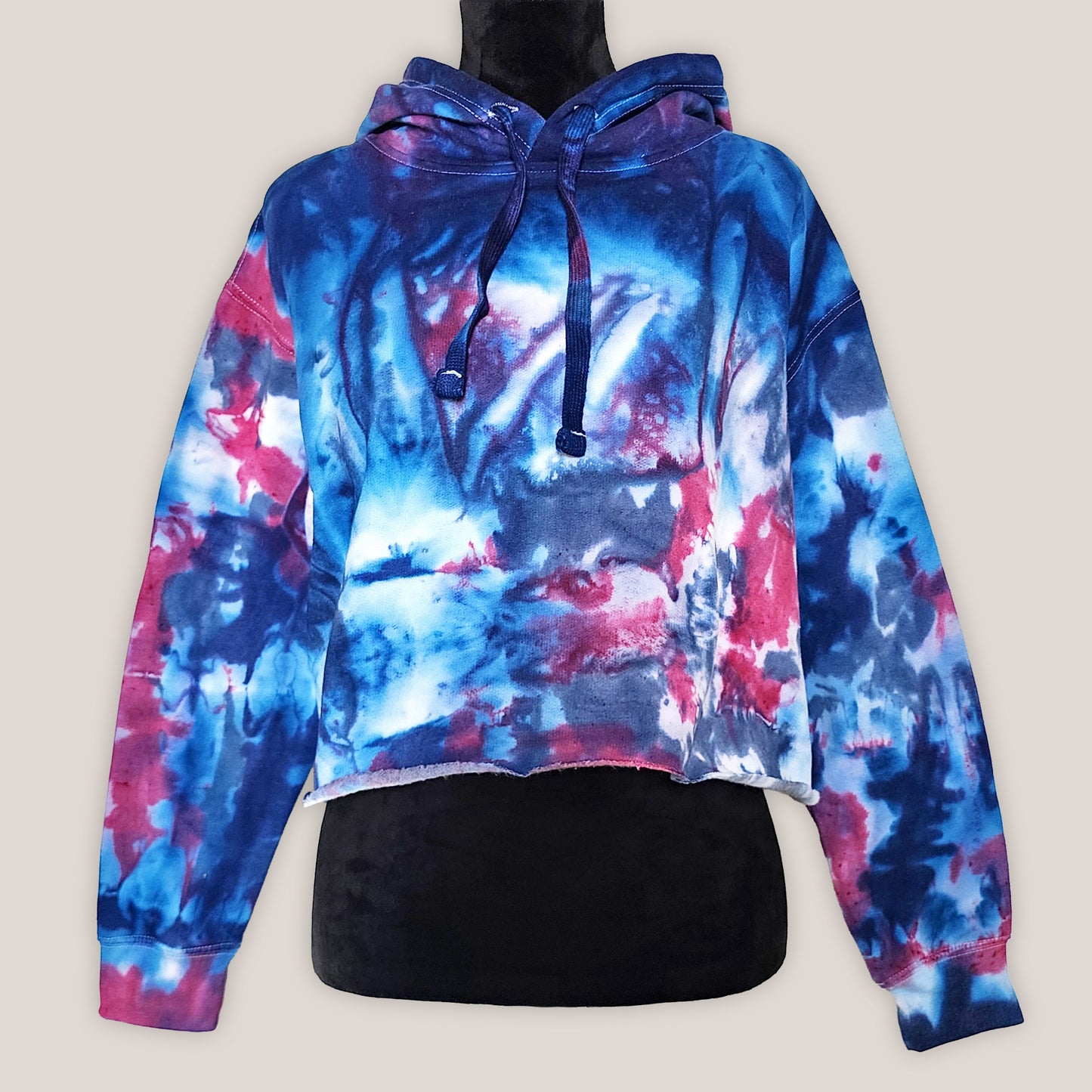Tie-dye hoodie with blue and pink patterns on a beige background
