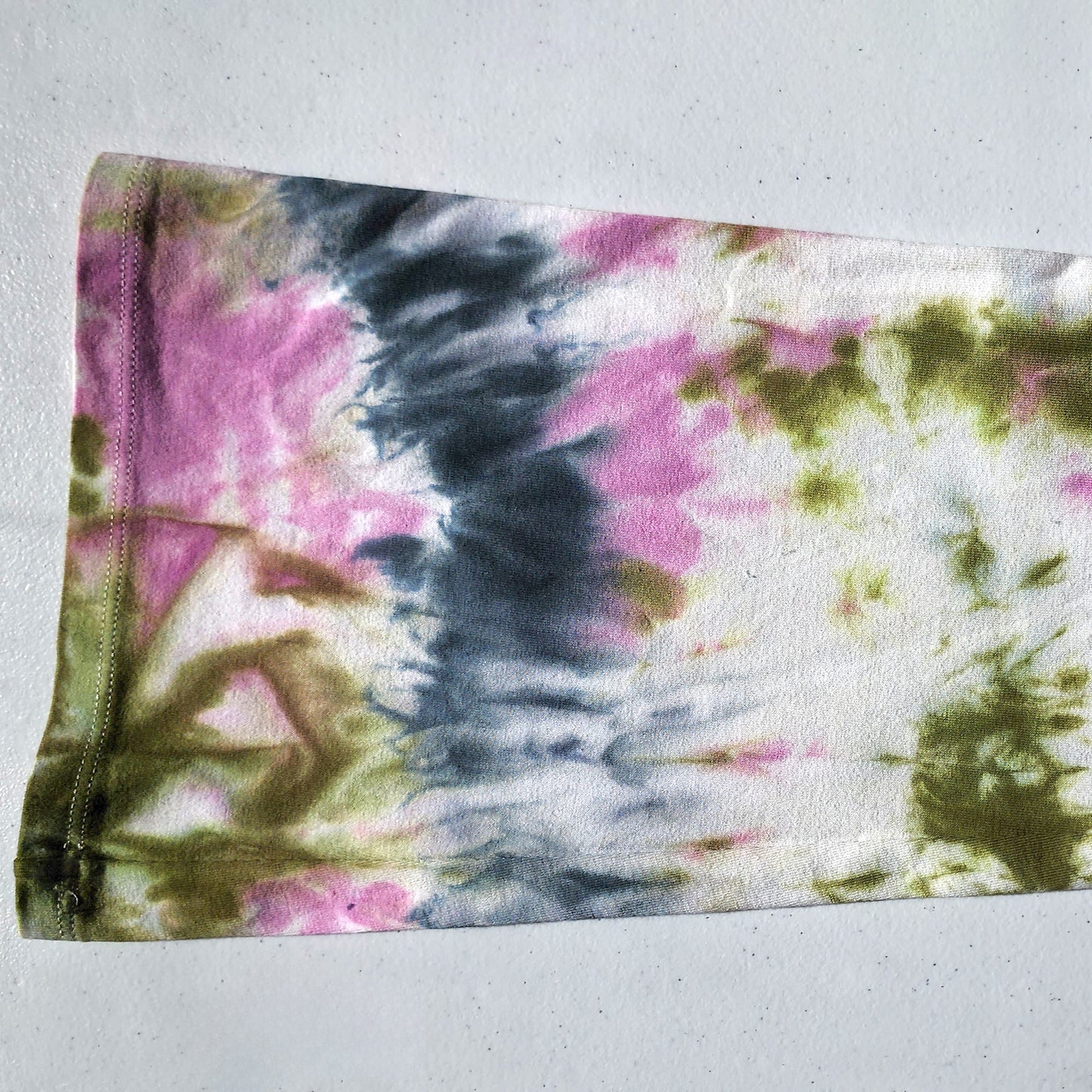 Tie-dye fabric with pink, green, and black patterns on a white background