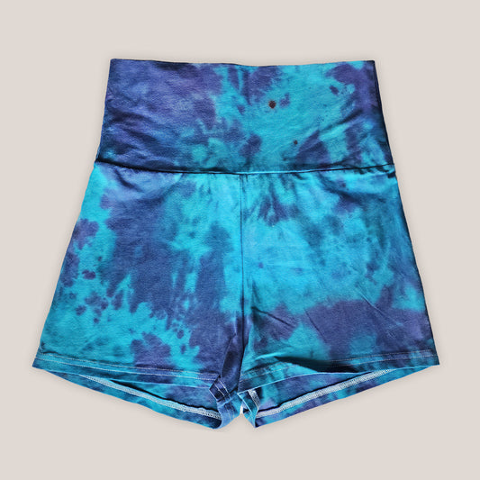 Blue cotton tie-dye shorts on a beige background