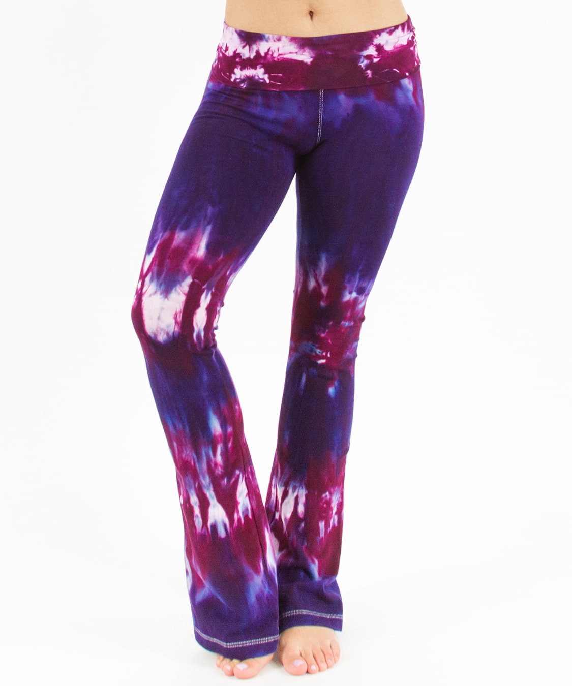 Woman wearing a pair of purple and pink tie dye yoga pants with a fold over waistband.