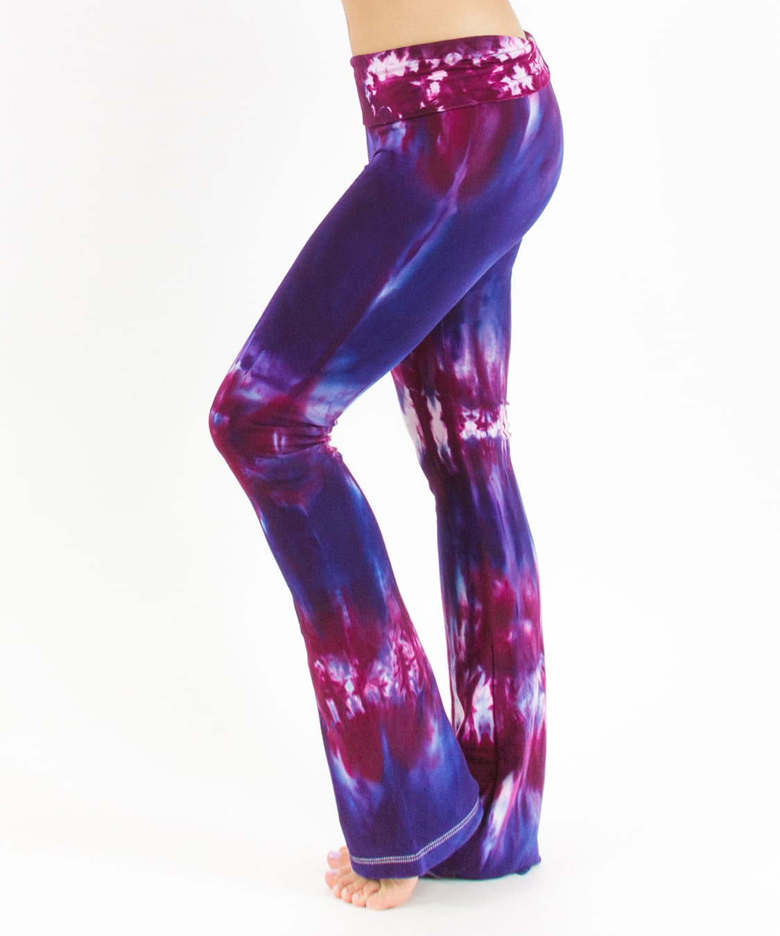 Woman wearing a pair of purple and pink tie dye yoga pants with a fold over waistband.