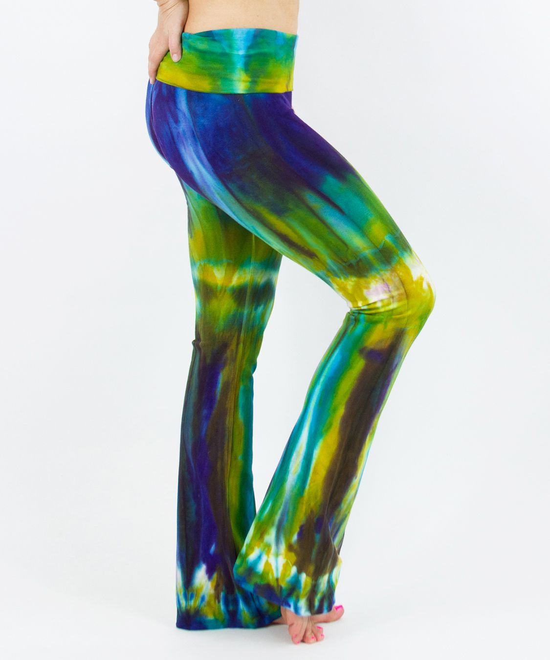 Woman wearing a navy blue and green tie dye yoga pants featuring a fold over waistband.