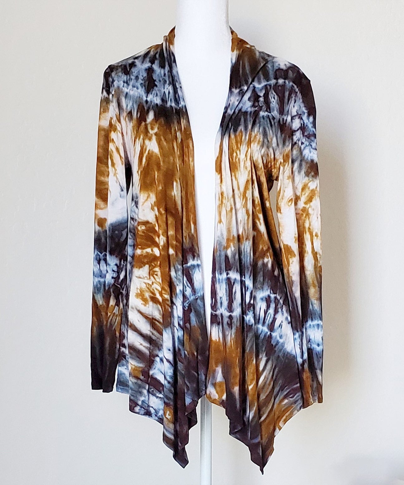 An amber and black tie dye cardigan featuring a waterfall drape in the front and long sleeves.
