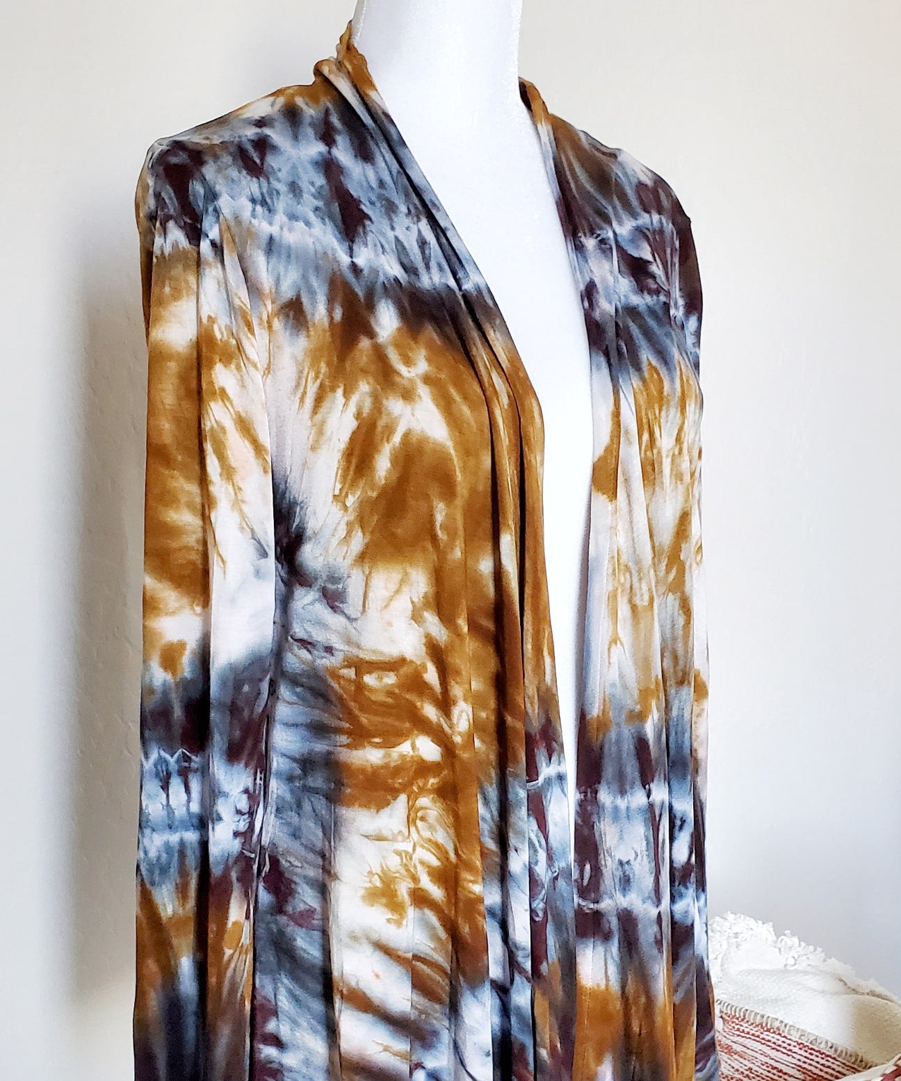 An amber and black tie dye cardigan featuring a waterfall drape in the front and long sleeves.