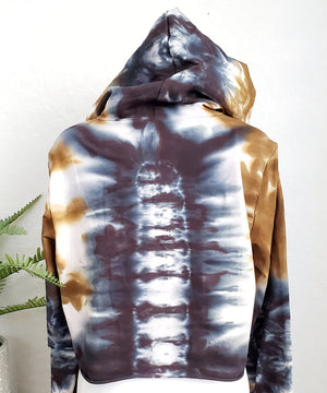 An amber and black tie dye hoodie crop top featuring long sleeves and draw strings.