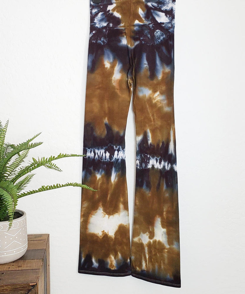 An amber and black tie dye pair of yoga pants featuring a wide waistband.