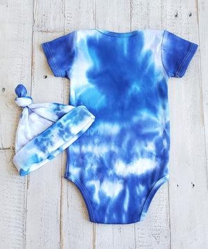 A blue and white tie dye baby bodysuit with a matching hat.