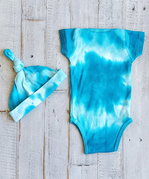 An organic tie dye baby bodysuit, hat, and blanket set in aqua blue.