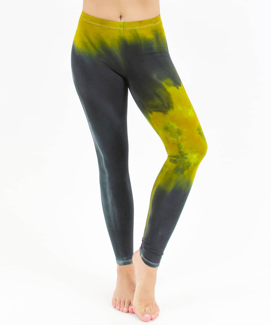 Woman wearing a pair of black and green chakra tie dye leggings made of sustainable cotton.