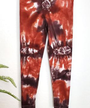 A burnt orange and brown tie dye pair of yoga leggings.