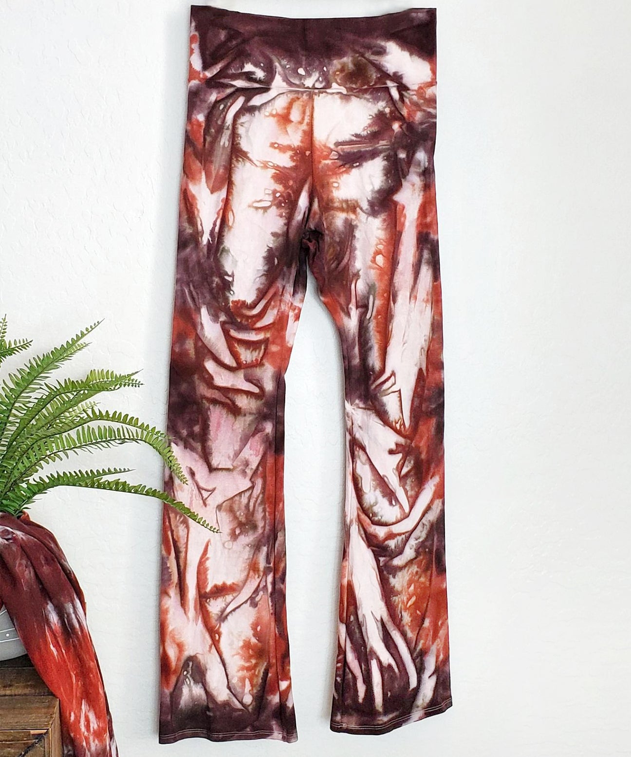 A rust organic and brown tie dye pair of yoga pants with a wide waistband.