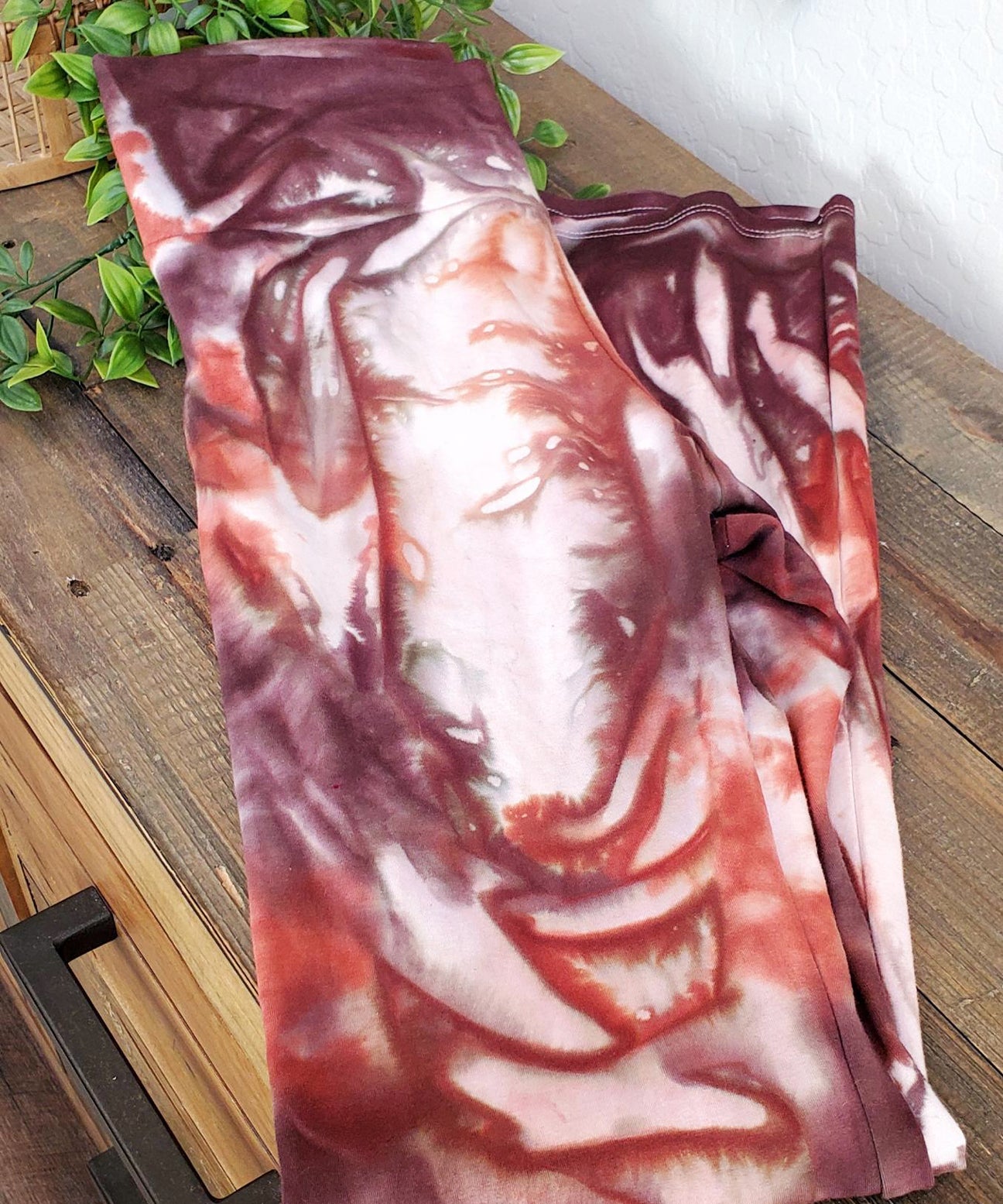 A rust organic and brown tie dye pair of yoga pants with a wide waistband.