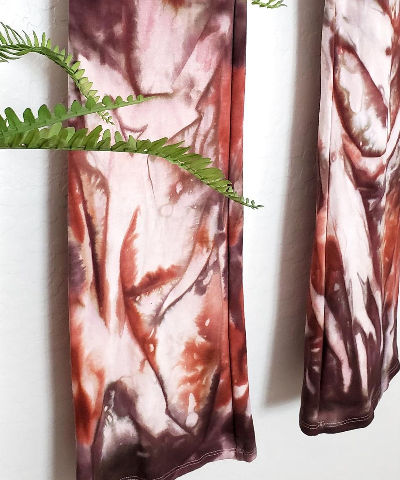 A rust organic and brown tie dye pair of yoga pants with a wide waistband.