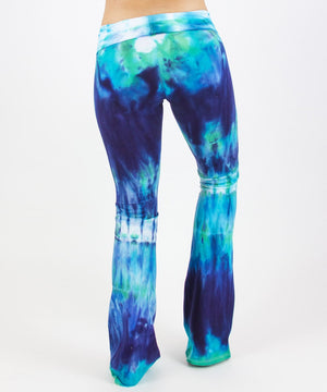Woman wearing the Galapagos Islands tie dye yoga pants that features hand-dyed hues of navy blue, teal, and aqua.  These pants include a fold over waistband that is also comfortable as maternity wear.
