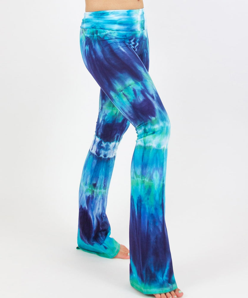 Woman wearing the Galapagos Islands tie dye yoga pants that features hand-dyed hues of navy blue, teal, and aqua.  These pants include a fold over waistband that is also comfortable as maternity wear.
