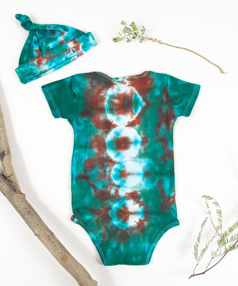 A teal and copper tie dye onesie and baby hat set by Akasha Sun.
