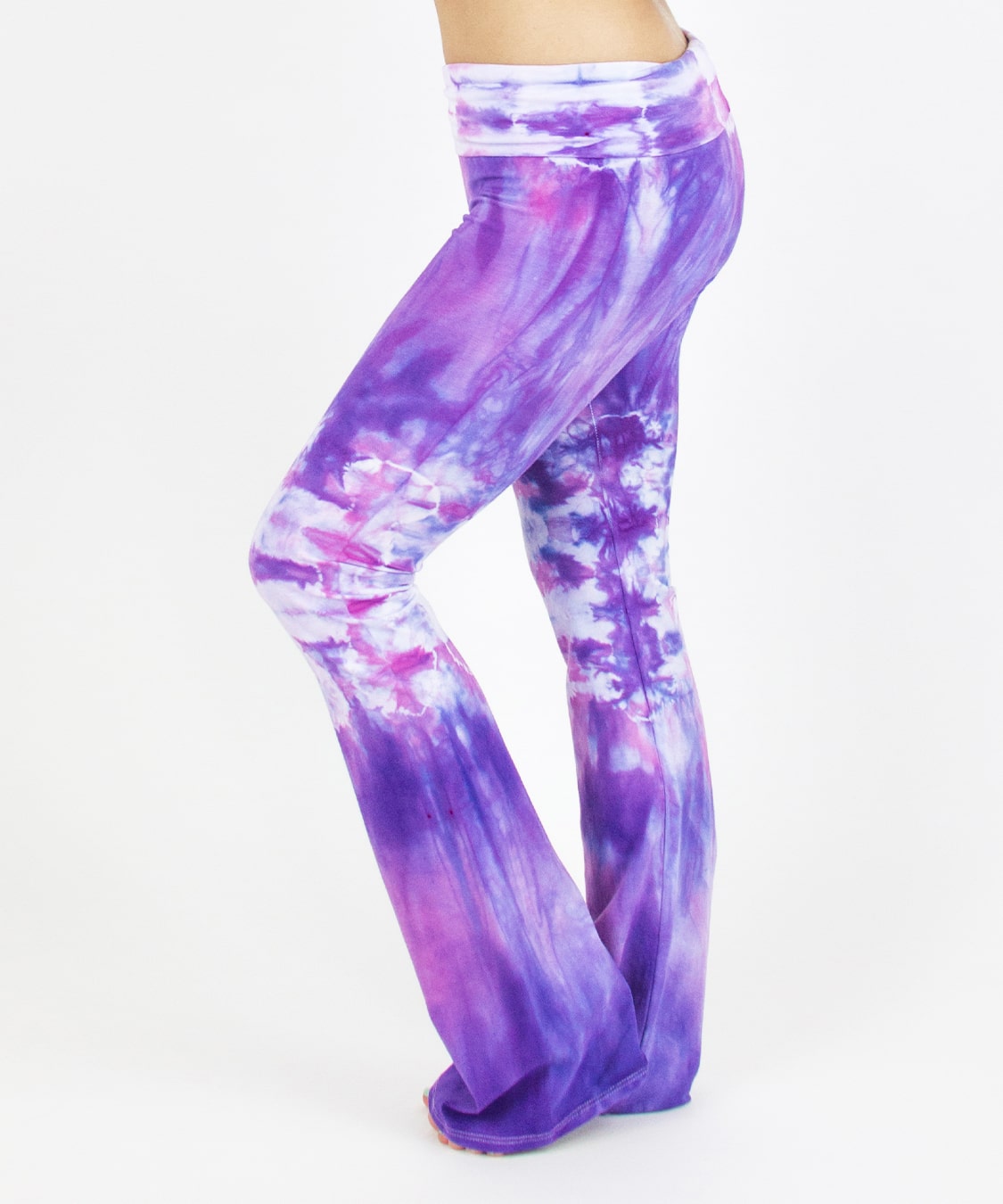 Woman wearing the Saint-Tropez tie dye yoga pants featuring the color purple, pink, and white.  The waistband can be folded down or up.