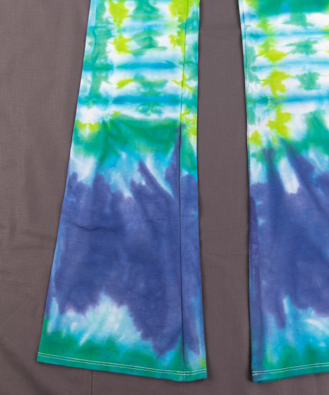 Teal, green, and blue tie dye yoga pants with a wide waistband and flare bottoms.
