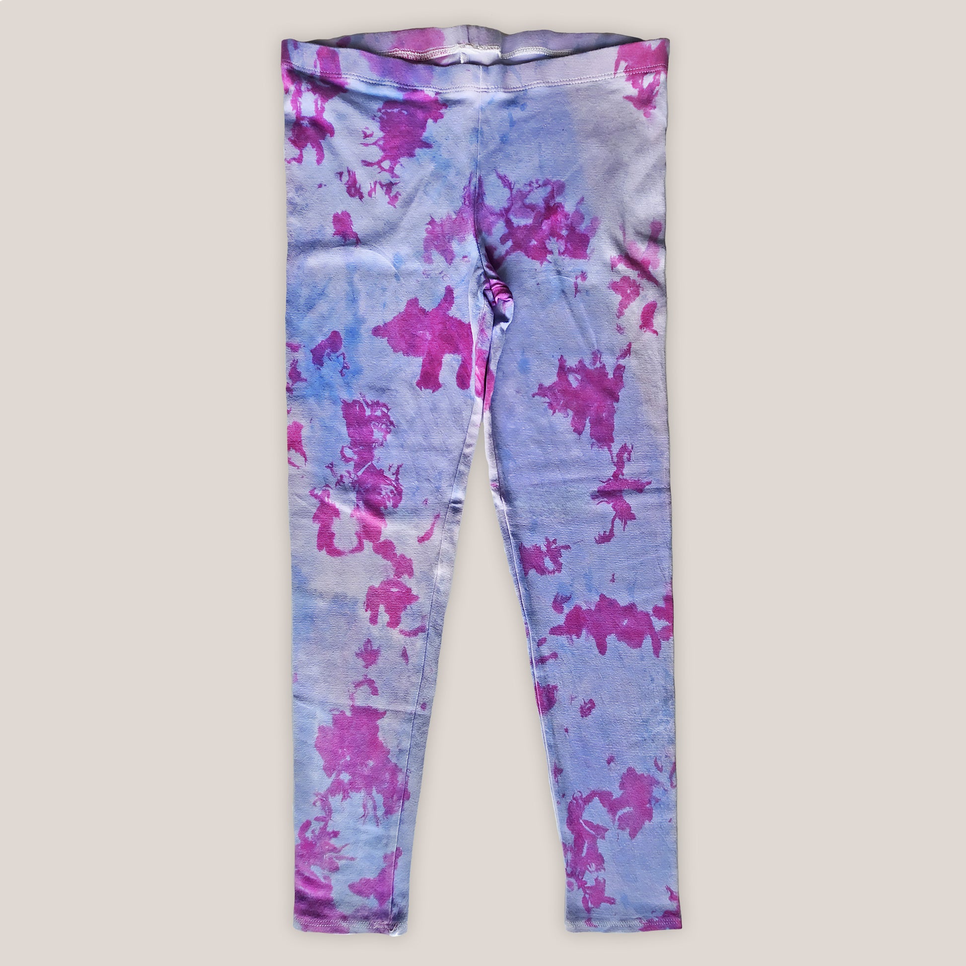 Purple leggings with pink tie dye patterns on a plain background
