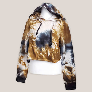 An amber and black tie dye hoodie crop top featuring long sleeves and draw strings.