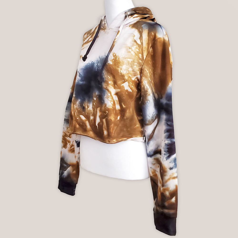 An amber and black tie dye hoodie crop top featuring long sleeves and draw strings.