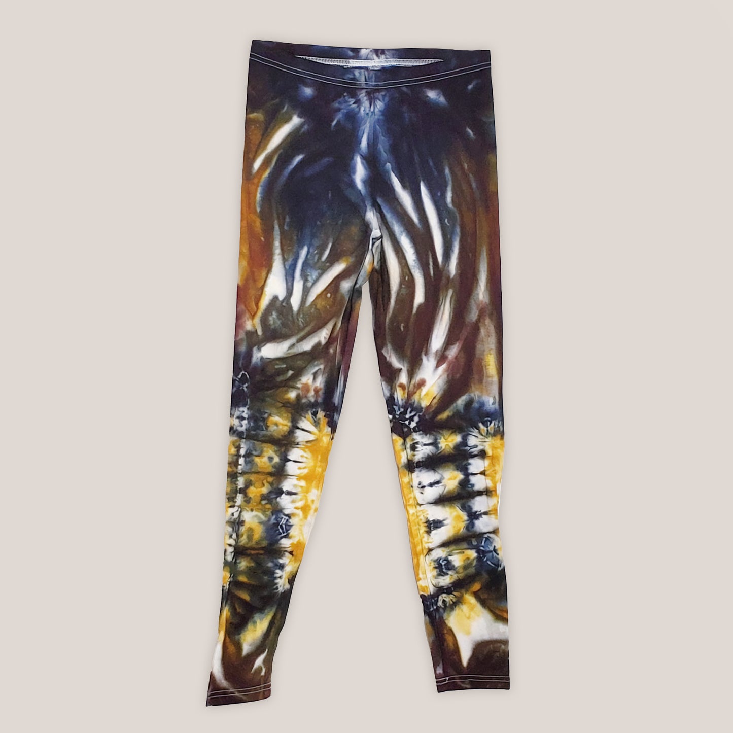 A pair of tie dye leggings in amber, black, and yellow.