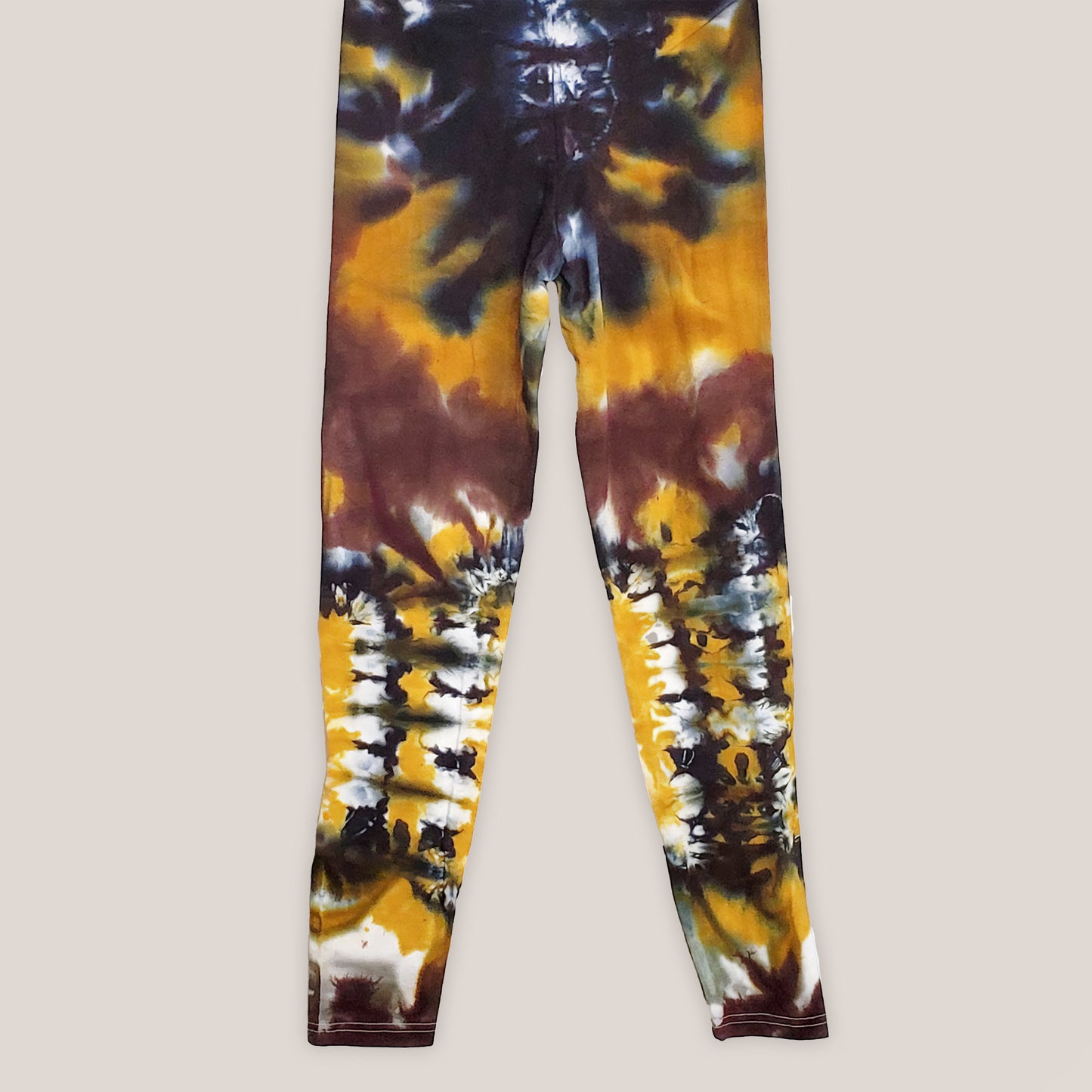 A pair of tie dye leggings in amber, black, and yellow.