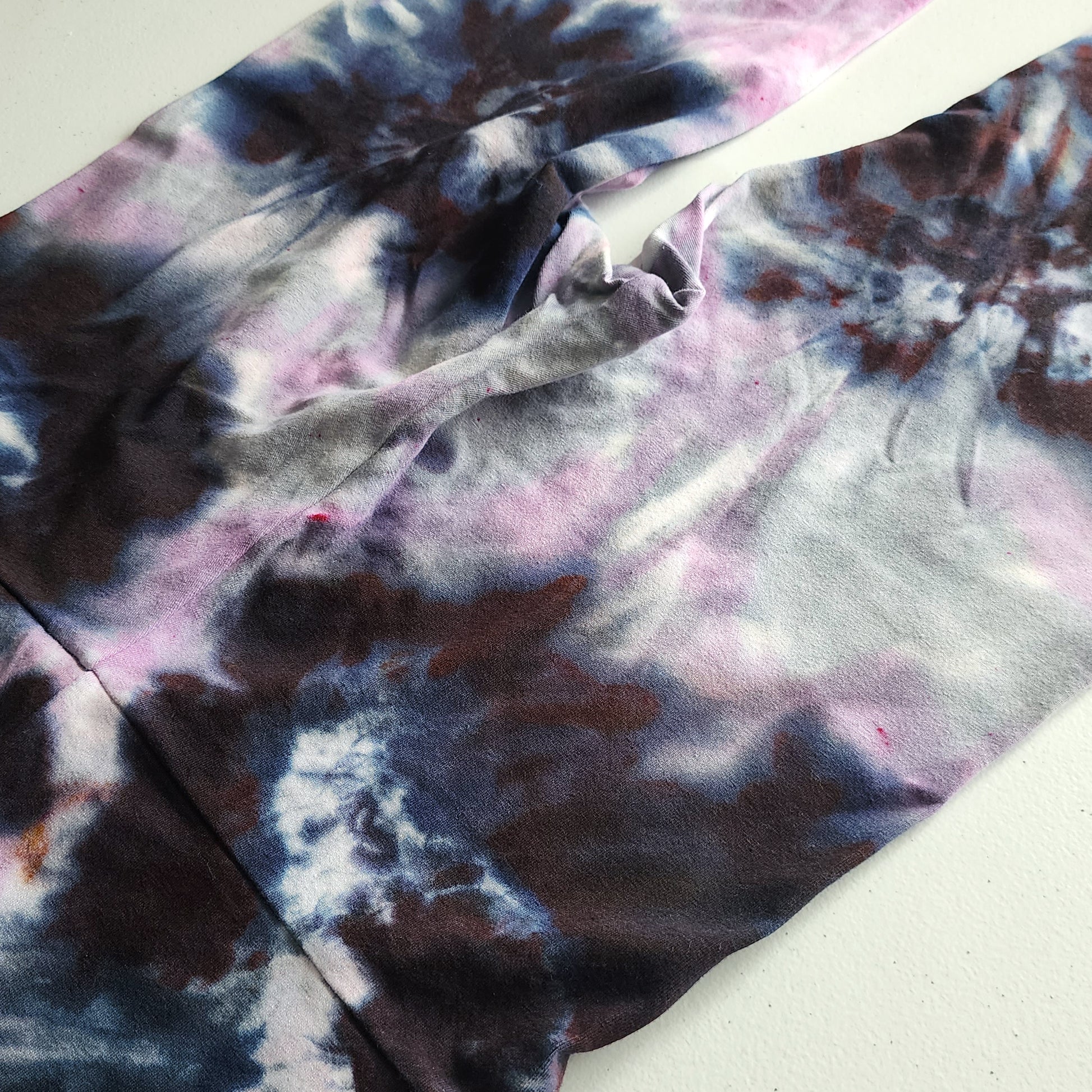 Close-up of tie-dye fabric with purple, black, and white patterns on a light background