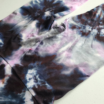 Close-up of tie-dye fabric with purple, black, and white patterns on a light background
