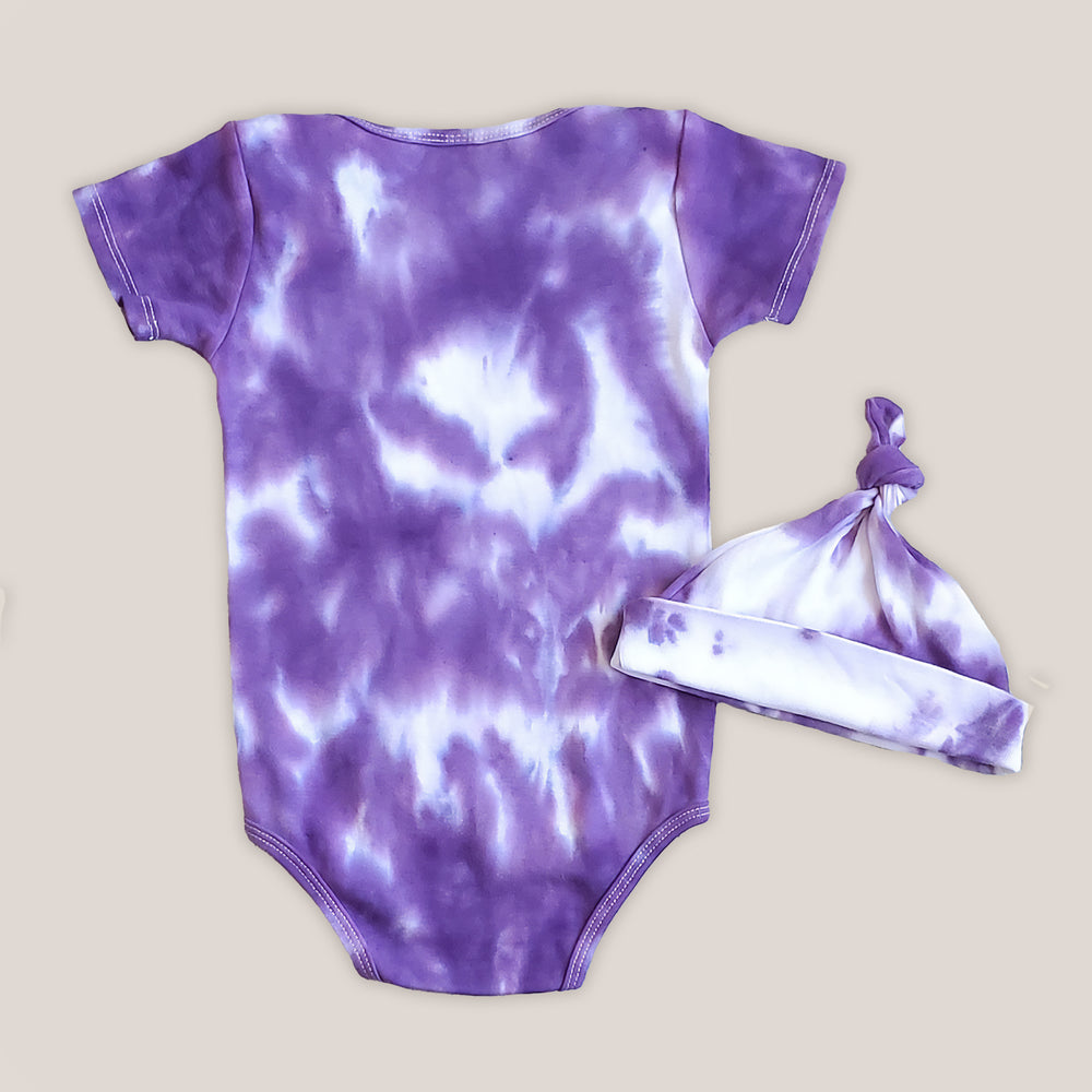 A purple and white tie dye baby bodysuit.