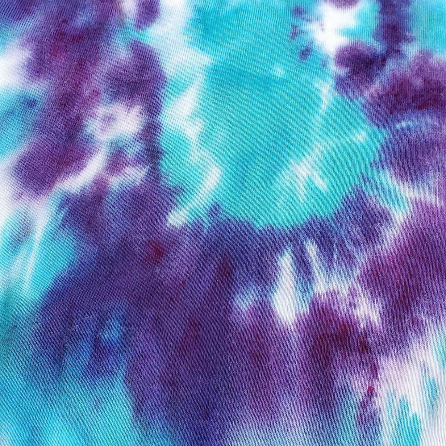 A purple and teal tie dye organic baby bodysuit.