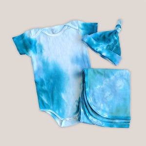 An aqua blue tie dye baby bodysuit, blanket, and hat set.