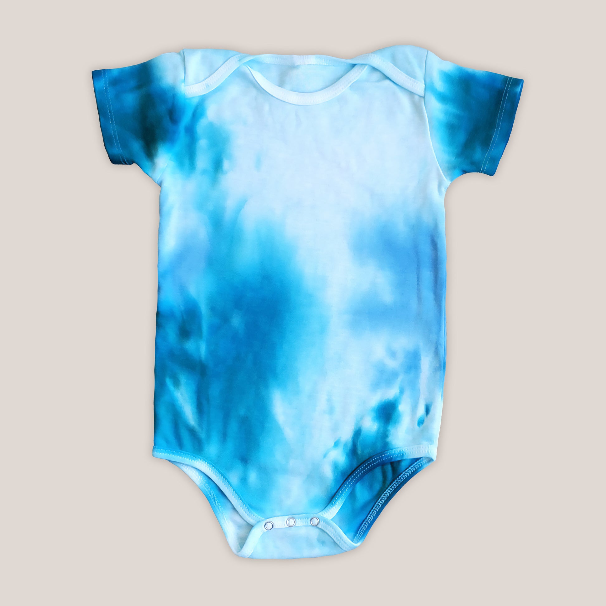 An aqua blue tie dye baby bodysuit, blanket, and hat set.