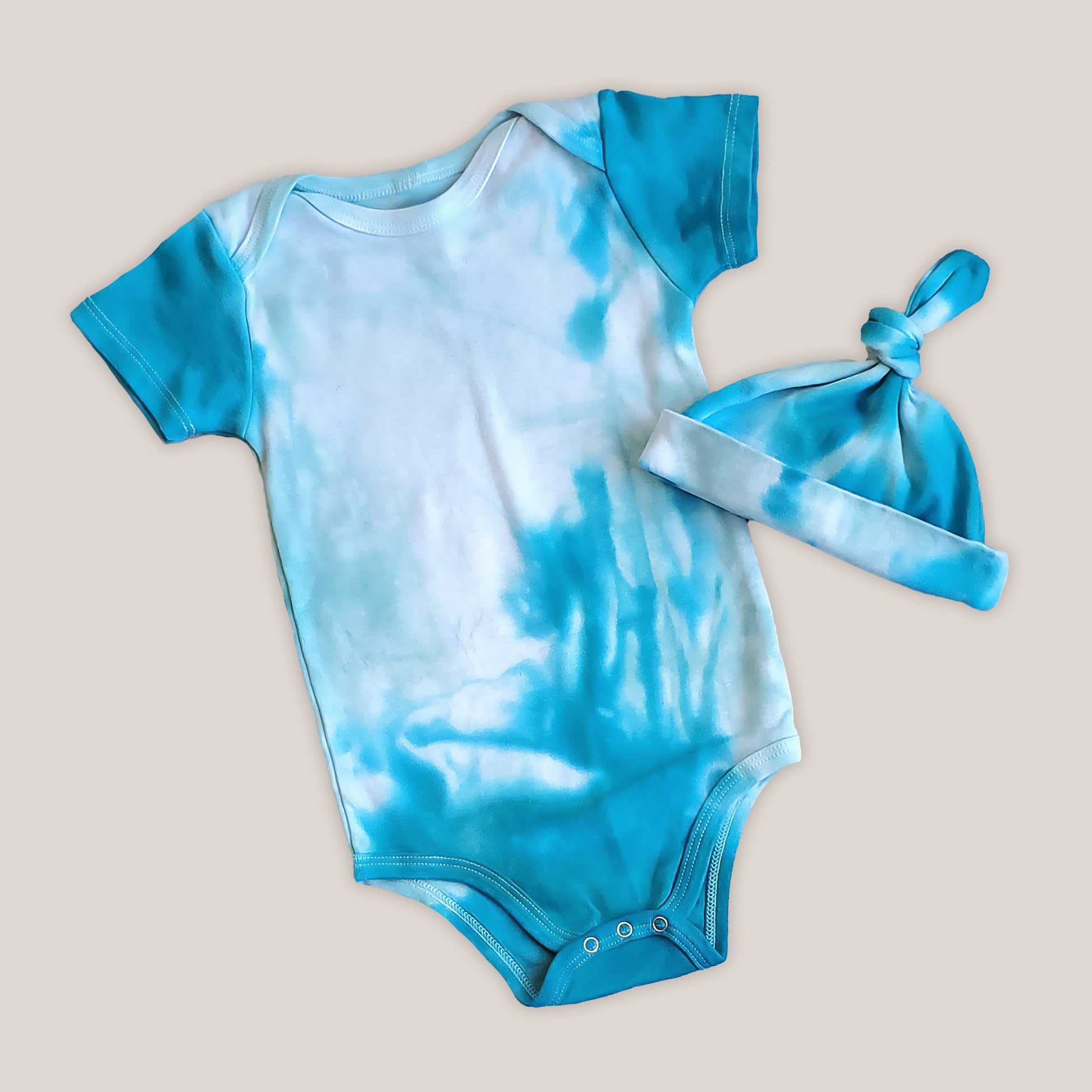 An organic aqua blue tie dye baby bodysuit and hat.