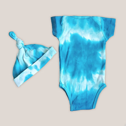 An organic tie dye baby bodysuit, hat, and blanket set in aqua blue.