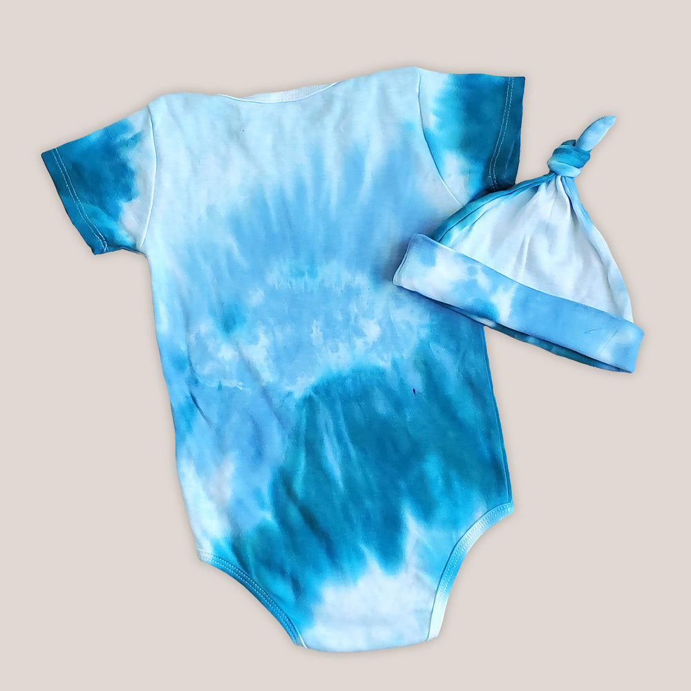 An aqua blue tie dye baby bodysuit, blanket, and hat set.